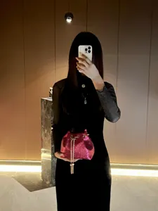 Detailed showcase of a sparkling pink bucket bag featuring delicate chain tassel accents.