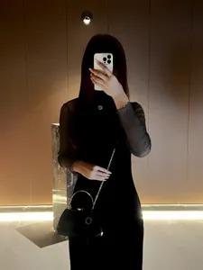 Details of the elegant black evening handbag featuring metal ring handle and chain strap.