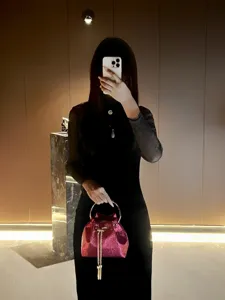 Detailed view of the sparkling pink bucket handbag with metal ring handle and chic chain tassel.
