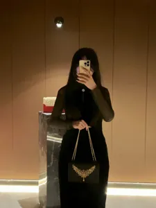 Elegante schwarze Kettenschultertasche für den Abend mit verziertem goldenen Flügelverschluss.