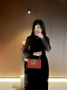 Vue détaillée du sac de soirée rouge avec des ornements floraux en cristal doré et chaîne.
