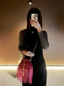 Detailed shot of a stylish pink sequin fringe bucket bag with metal chain strap design.