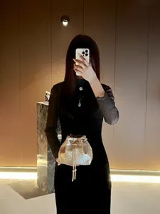 Details of the shiny gold bucket bag, featuring sparkling sequins and a delicate chain strap.