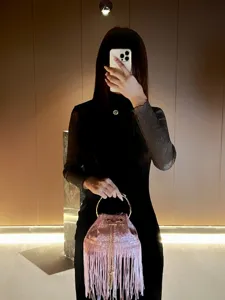 Fringe evening bucket bag detail showing sparkling pink glitter, gold ring handle and long tassels.