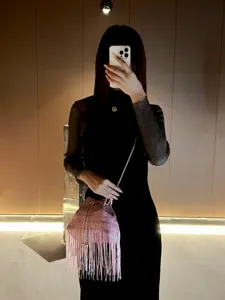 Detailed view of the pink fringe bucket evening bag worn, showcasing stylish chain strap.