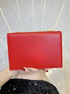 Dettaglio borsa a catena in pelle rossa che mostra consistenza liscia e accessori dorati.