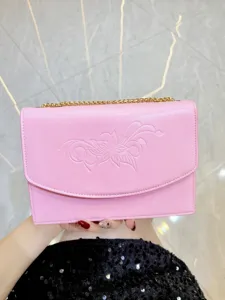 Vista dettagliata della borsa a spalla rosa in pelle con motivo floreale e catena dorata.