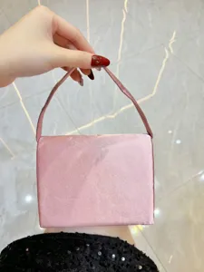 Detailansicht der eleganten rosafarbenen Satintasche, die edle Stofftextur und Griff zeigt.