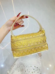 Detailansicht der ethnischen gelben bestickten Abendhandtasche mit Pailletten und kurzem Griff.