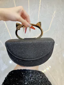 Vue détaillée du sac de soirée pailleté noir avec poignée en métal en forme d'oreilles de chat.