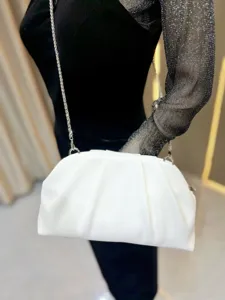 Close-up detail of white pleated shoulder bag with silver chain strap, elegant clutch style.
