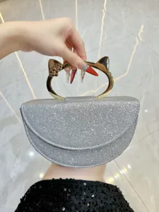 Vue détaillée du sac de soirée argenté scintillant doté d'une poignée en métal chat doré.