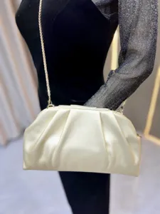 Elegant gold pleated clutch bag with metal chain strap, luxury fashion accessory detail.
