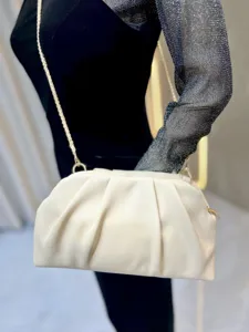 Detail shot of women's stylish pleated clutch bag, elegant cream white finish with gold chain.