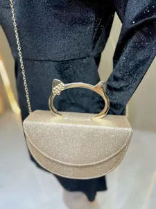Sac de soirée boîte dorée scintillante avec poignée métallique unique en forme d'oreilles de chat.