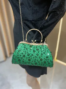 Detailopname van de glinsterende groene pailletten avondtas met gouden handvat.