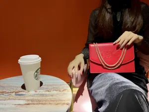Primo piano dettagliato di una elegante borsa rossa a catena con motivo floreale.