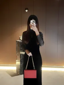 Dettaglio di borsa a tracolla rossa con catena dal design minimalista ed elegante.