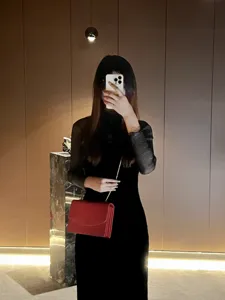 Dettaglio di una elegante borsa a tracolla rossa strutturata abbinata a un look chic.