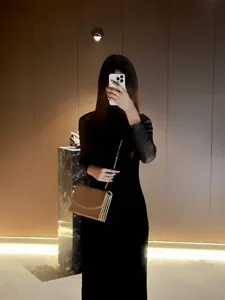 Dettaglio di una borsa a tracolla in pelle cammello con catena e design a fisarmonica.