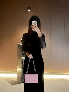 Vista dettagliata di elegante borsa a tracolla rosa da donna con catena dorata e patta.