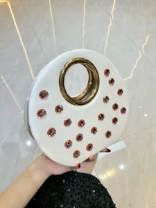 Magnifique sac de soirée rond avec poignée anneau doré et strass roses élégants.