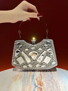 Primer plano detallado de un bolso de noche brillante con pedrería y diseño de cristal geométrico.
