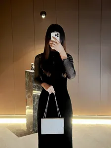 Dettaglio elegante di borsa a tracolla bianca con catena e design minimalista in metallo.
