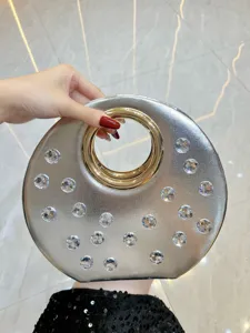 Gros plan de l'élégant sac de soirée rond avec des strass scintillants et une poignée dorée.