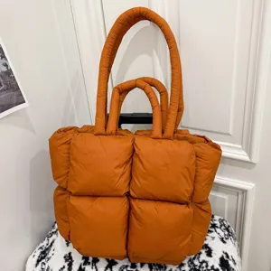 Orange quilted puffer tote bag for women, stylish padded shoulder bag with dual handles.