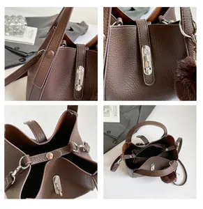 Korean style brown leather bucket bag detail view with metal lock closure and plush pom-pom pendant.