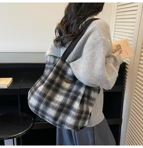 Detailed view of the vintage plaid tote bag worn on shoulder in a cozy indoor setting.