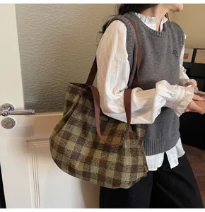 Detailed view of a vintage green and brown plaid tote shoulder bag worn in a cozy room setting.
