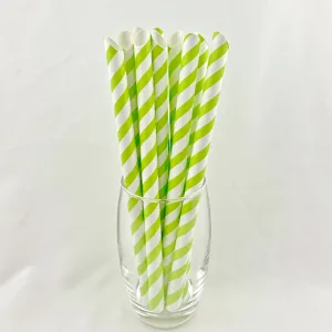 Green and white striped paper straws detail view, eco-friendly drinking straws in glass cup.