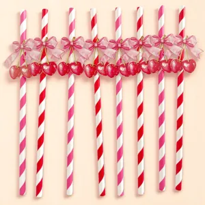Decorative striped paper drinking straws with pink bows and cherry charms for holiday party.