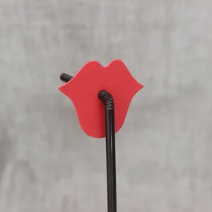 Close-up of creative red lips paper decoration on black plastic party drinking straw.
