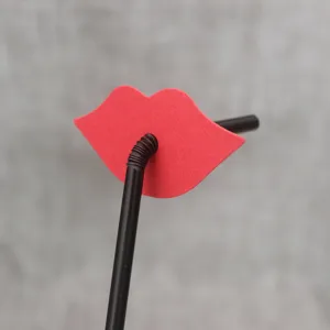 Close-up detail of party red lip paper decoration attached on black plastic drinking straw.