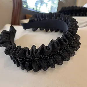 Close-up detail of the black pleated ruffle headband featuring sparkling crystal beads.