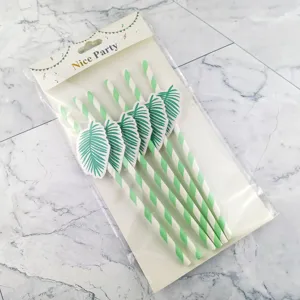 Pajitas de papel a rayas verdes y blancas con decoración de hojas de palma para fiestas.