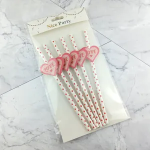 Close-up detail of eco-friendly paper drinking straws with red polka dots and love heart decor.