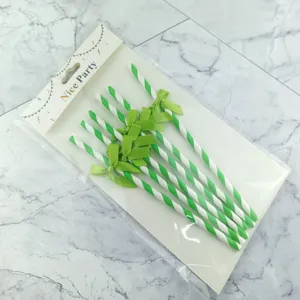 Detailed view of disposable green and white striped paper straws with cute decorative bows for parties.