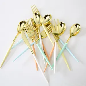 Vue détaillée de couverts jetables en plastique doré avec des poignées colorées pour fête d'anniversaire.