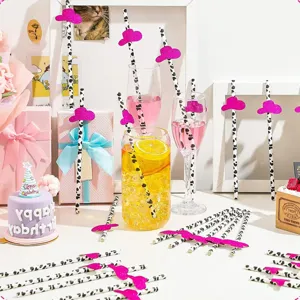Vue détaillée de pailles en papier à motif vaches avec mini-chapeaux roses pailletés.