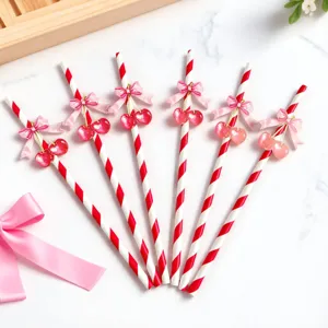 Red and white striped paper straws featuring pink bows and cherry charms, perfect for party decor.