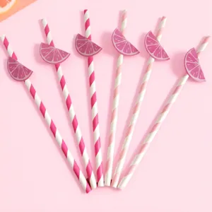 Primer plano de pajitas de papel a rayas rosas decoradas con rodajas de limón para fiestas.