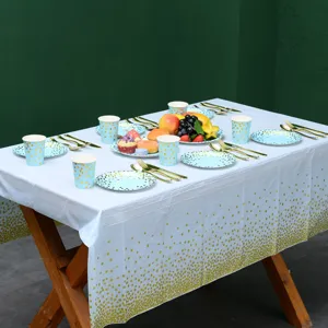Vue détaillée d'une nappe de fête à pois bleus et dorés avec assiettes et tasses assorties.