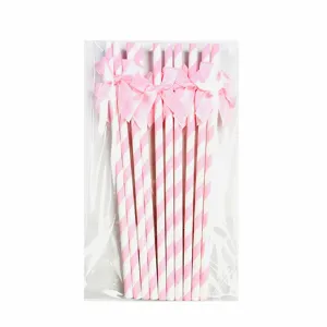 Pink and white striped paper straws with sweet bow decorations for party desserts detail.