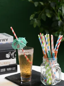 Colorful striped paper straws with mini umbrellas in glass jar, detail shot for party drinks.