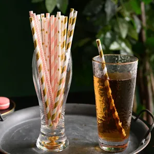 Biodegradable paper straws detail view, pink and gold foil striped design for party drinks.