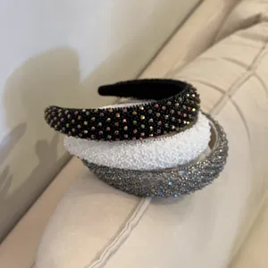 Gedetailleerde close-up van strass en kraaltjes haarband met hoge schedel in zwart, wit en grijs.